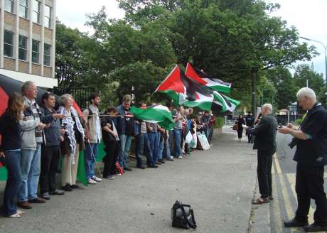 Protesters wall off the embassy gate, while Diarmuid recites his poem.