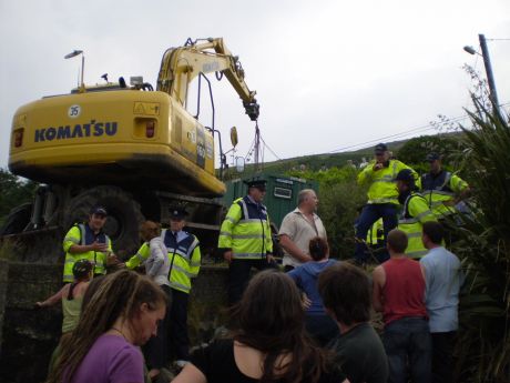 The digger hoists the illegal portacabin into place. 